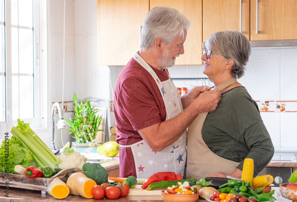 Two smiling seniors in the home kitchen prepare vegetables together for a healthy soup. Joyful elderly couple who appreciate a vegetarian lifestyle and enjoy their retirement Two smiling seniors in the home kitchen prepare vegetables together for a healthy soup. Joyful elderly couple who appreciate a vegetarian lifestyle and enjoy their retirement