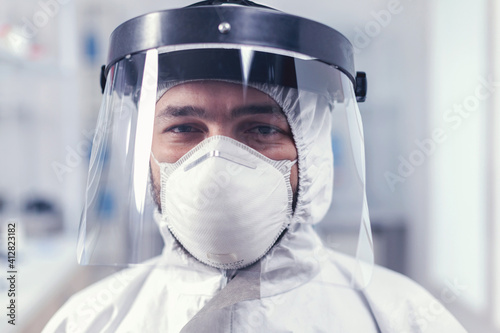 Portrait of biochemist in science laboratory wearing ppe equipment for covid19. Overworked researcher dressed in protective suit against invection with coronavirus during global epidemic. photo