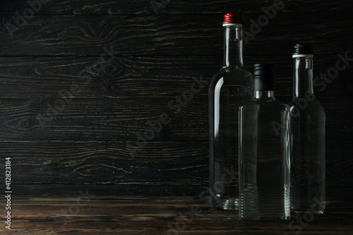 Blank bottles of vodka on wooden background, space for text