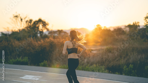 Woman running alone at beautiful sunset on the road. Summer sport and freedom concept. Athlete training on dusk. Runner feet running on road closeup on shoe. woman fitness sunrise jog workout 