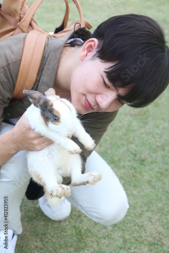 Say hello to a male tourist with a rabbit in an open zoo.