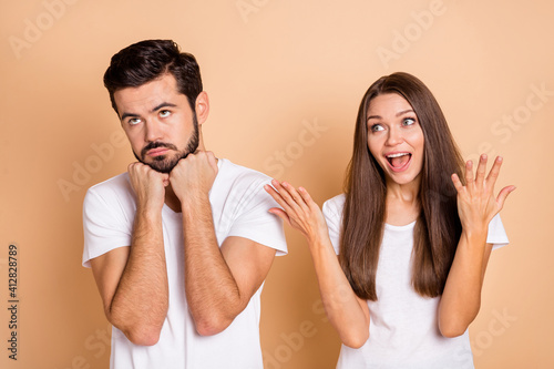 Photo of stressed quarrel married couple dressed white t-shirt looking empty space rising arms isolated beige color background