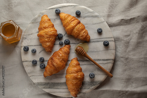 Homemade croissants with blueberries and honey on marble tray top view with copy space. High quality photo