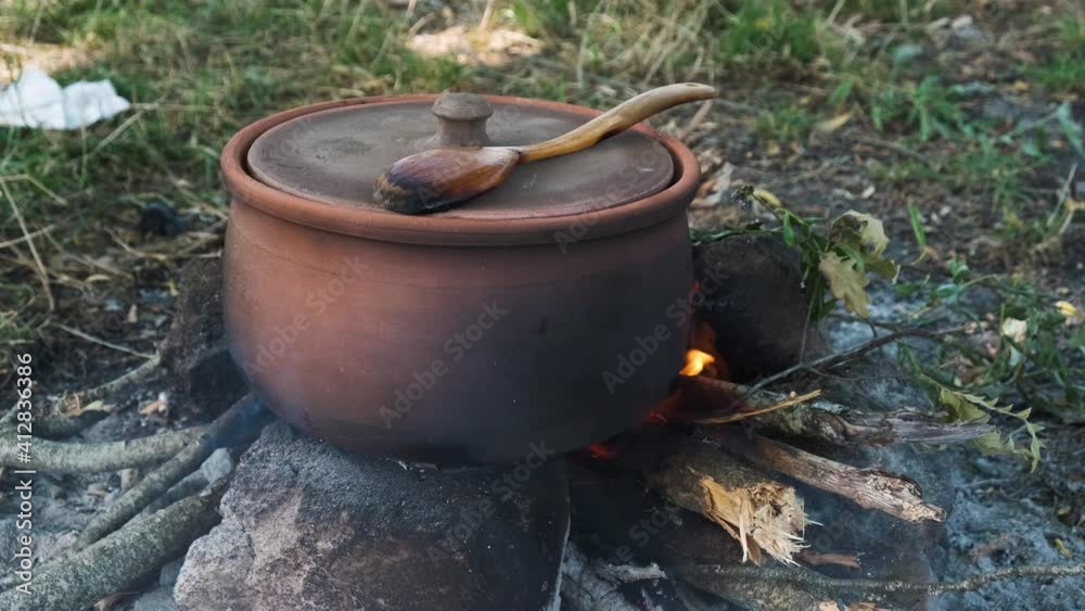 Clay Pot on Camp Fire in Forest. Cooking Meal with Traditonal Cooker. Slow Motion Close Up Shot. Clay Pot on Camp Fire in Forest. Cooking Meal with Traditonal Cooker. Slow Motion Close Up Shot.
