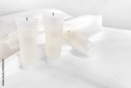White cosmetic products tube on stand with fabric drapery. Mockup in right side
