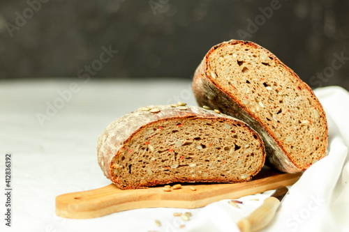 Black sliced bread on a wooden board with a knife against a white background. Blurred background. Copy space