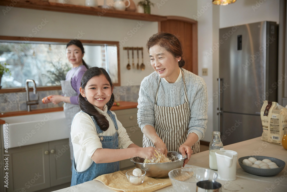 Happy adorable little child girl in apron enjoying cooking homemade pastry together with family at home.