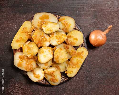 Baked potatoes with onion on a wooden background