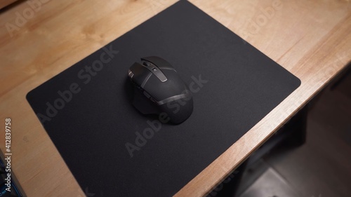 Mouse gamer en color negro con varios botones, sobre mousepad de color negro