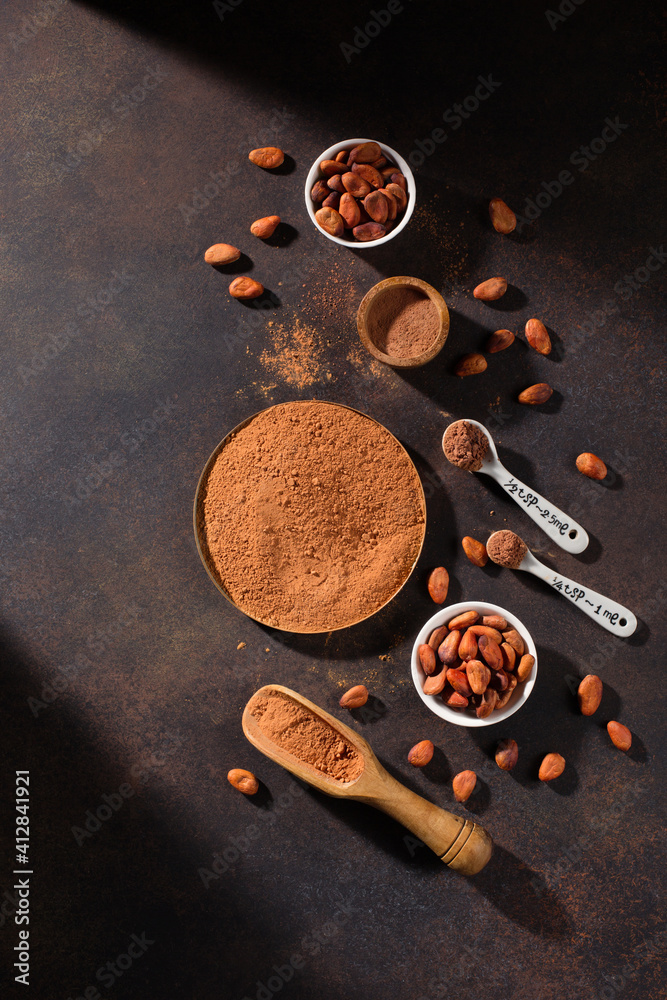 Bowls with organic cocoa powder and aromatic raw cocoa beans on dark rustic wooden background. Bowls with organic cocoa powder and aromatic raw cocoa beans on dark rustic wooden background.