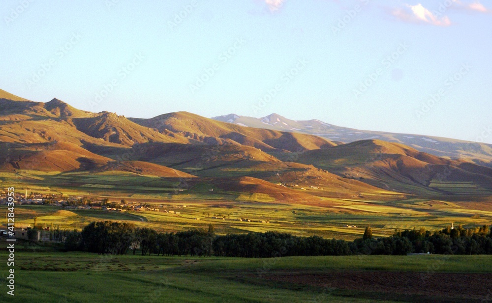 A clear, panoramic shot of valleys near a path which is filled with green grass and trees side by side. A clear, panoramic shot of valleys near a path which is filled with green grass and trees side by side.