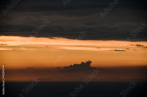 beautiful view of clouds in orange sky above the ocean horizon line © fesenko