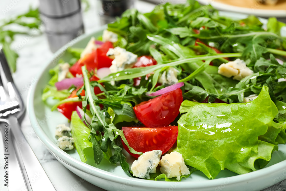Delicious salad with arugula and tomatoes on white table, closeup