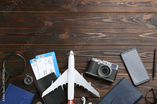 Flat lay composition with toy airplane and travel items on wooden background. Space for text