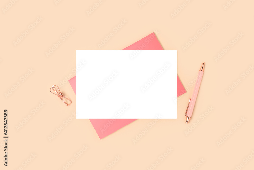 Empty paper card mockup and pink stationery on a beige background. Minimalistic business workspace. Empty paper card mockup and pink stationery on a beige background. Minimalistic business workspace.