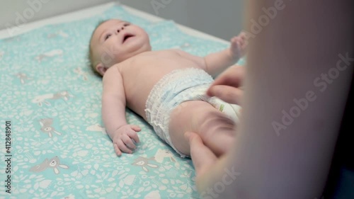 Newborn baby development. 3 months baby boy. Mother massaging and tickling small baby legs