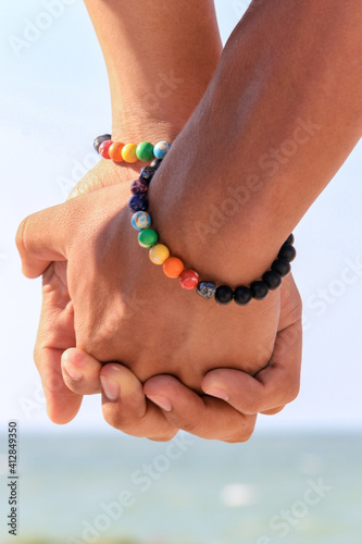 men holding hands with gay pride bracelets