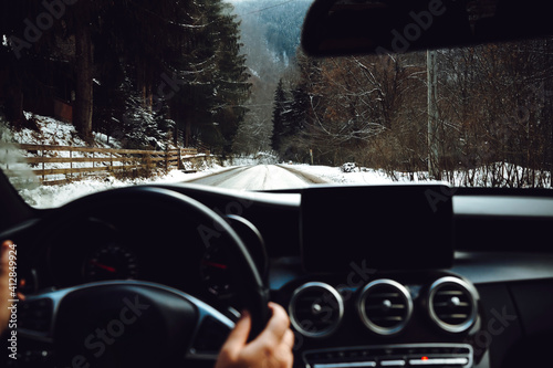 Fototapeta Naklejka Na Ścianę i Meble -  Close up details of driver driving a modern car. Inside of car details, drivers view through windshield. Winter mountain landscape