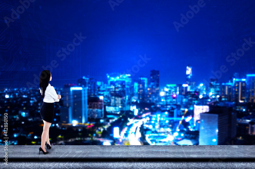 Businesswoman looking at glowing lights skyscrapers