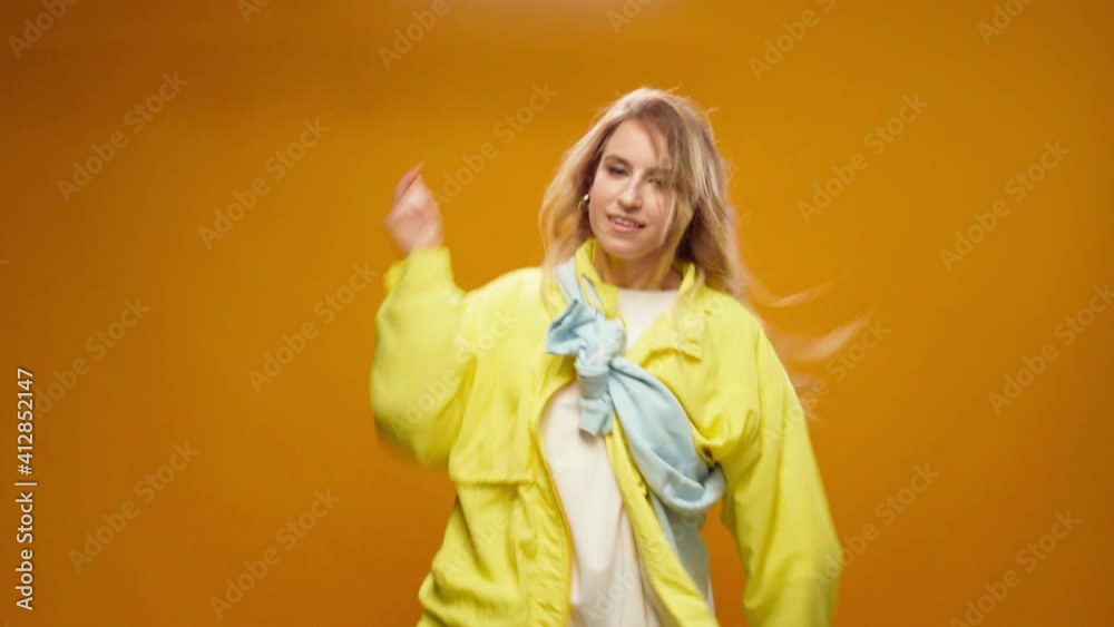 Woman professional dancer dancing in studio against yellow background Woman professional dancer dancing in studio against yellow background