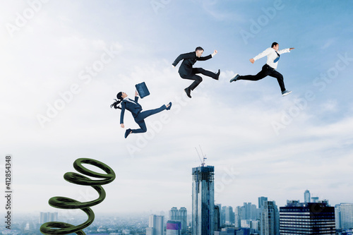 Foto Three business people use a springboard to jumping
