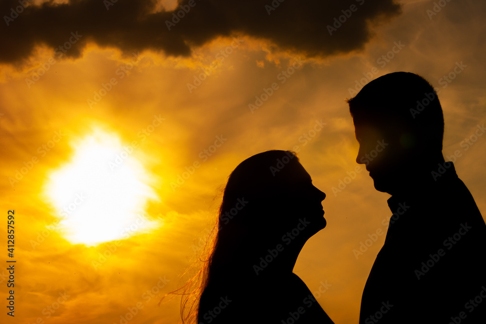  Silhouette of a loving couple cuddling during a golden sunset, showing the concepts of love, couple, romance, valentine, togetherness