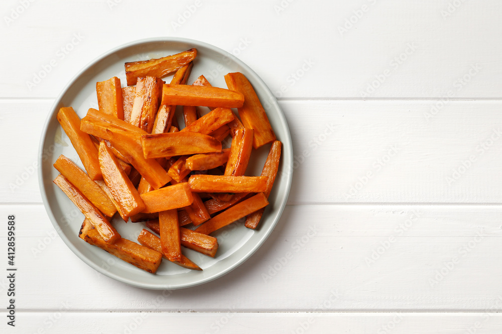 Plate with deliciously cooked sweet potatoes, rosemary, sauce and spices, herbs on a wooden table Plate with deliciously cooked sweet potatoes, rosemary, sauce and spices, herbs on a wooden table