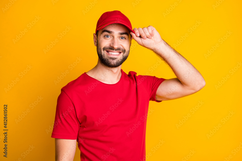 Close-up portrait of nice content cheerful guy mailman touching cap isolated over vibrant yellow color background
