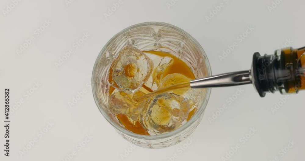 Top view of pouring whiskey into rocks glass with ice. Using bottle pourer. Alcoholic beverage. Bartender tools. Isolated on white background. Top view of pouring whiskey into rocks glass with ice. Using bottle pourer. Alcoholic beverage. Bartender tools. Isolated on white background.
