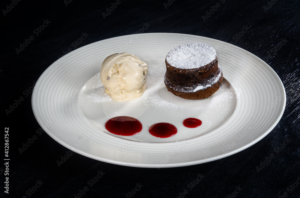 Dessert of ice cream and cupcake on a white plate on a black background Dessert of ice cream and cupcake on a white plate on a black background