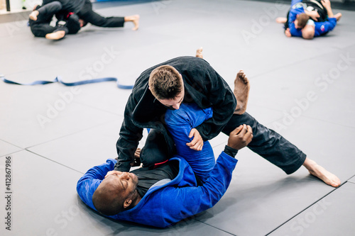 Two Jiu-Jitsu practitioners fighting on the mat in training photo