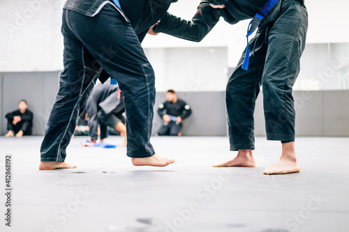 Two Jiu-Jitsu practitioners fighting on the mat in training photo