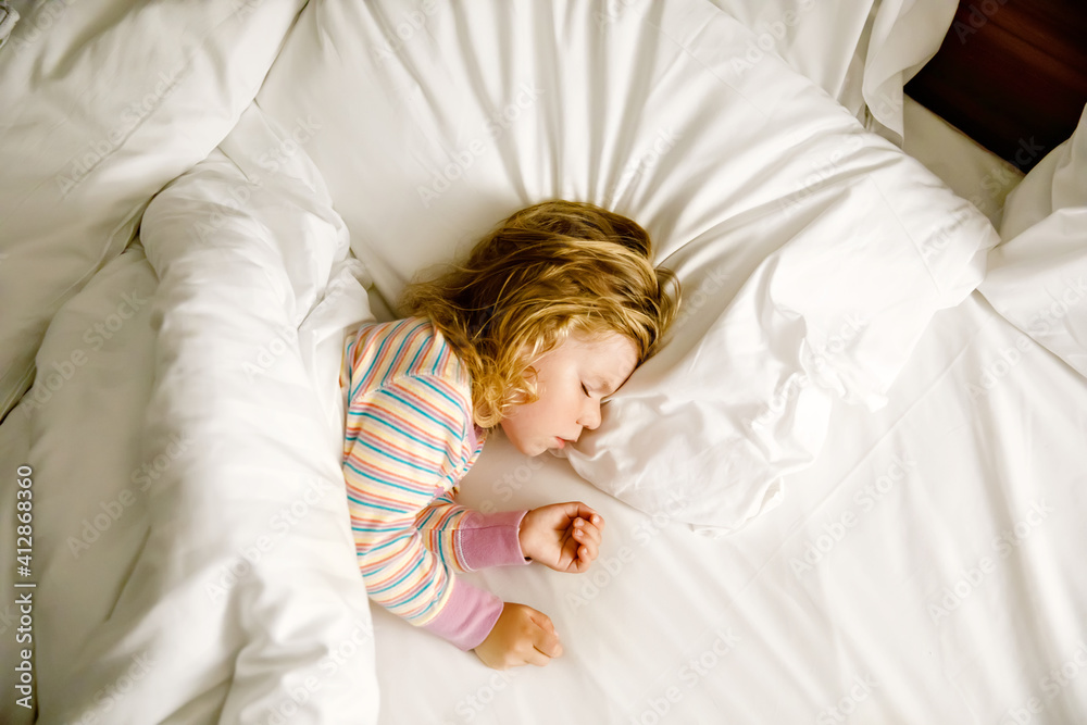 Cute little toddler girl sleeping in big bed of parents. Adorable baby