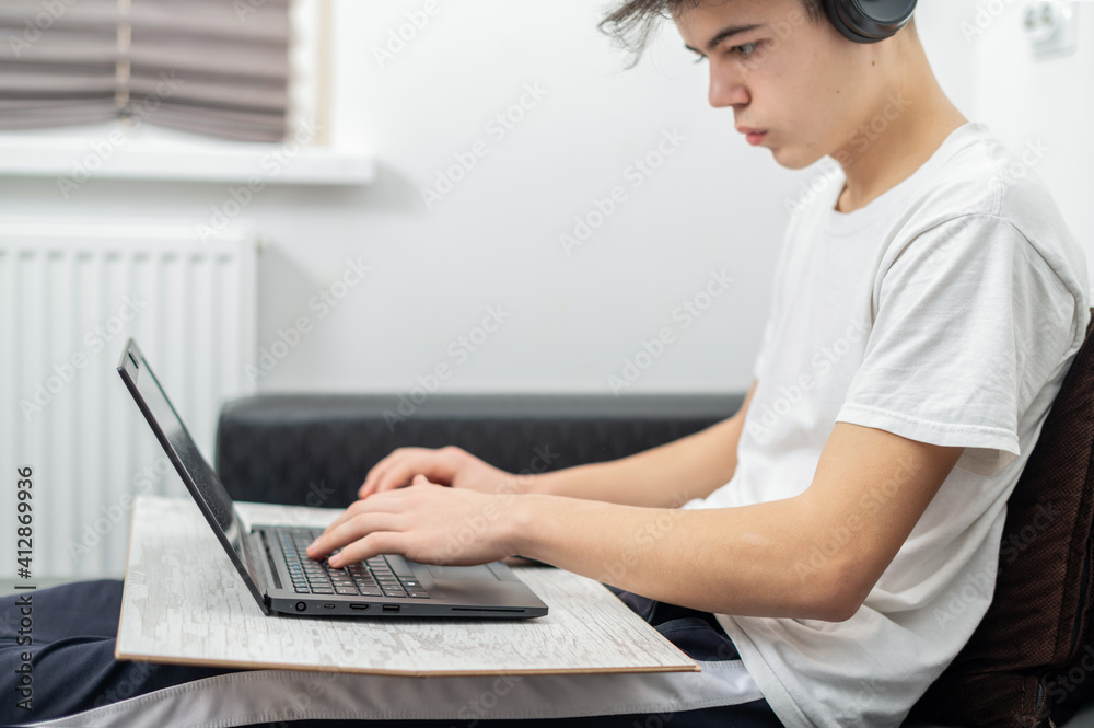 Fototapeta premium Teen boy using laptop at home