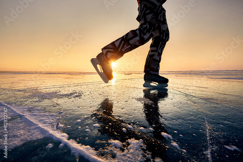 Ice skating on frozen lake at orange sunrise