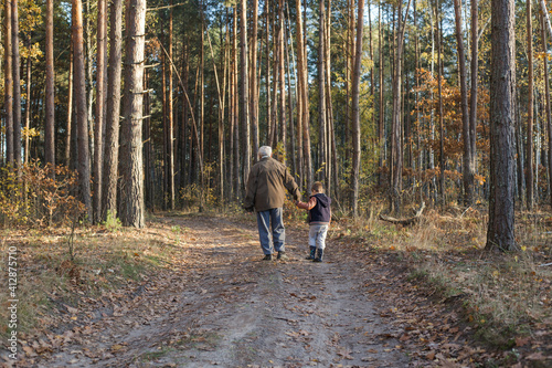 Happy child with Grandfather playing at the forest. Grandpa retiree. Retirement parent. Portrait of pensive senior man  and his grandson. Senior man having fun with his grandchild outdoor. © Maria