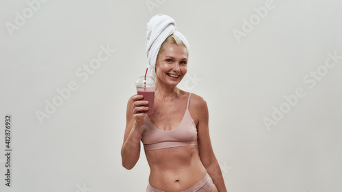Beautiful middle aged caucasian woman raising smoothie