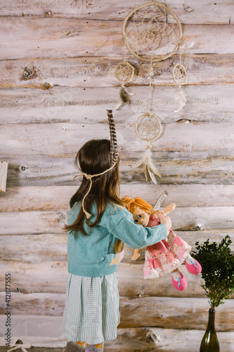 little indian girl holding a doll in her hands. dreamcatcher.