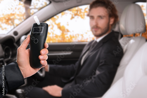 Fotografie Police officer with breathalyzer and man in car