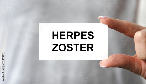 the doctor's gloved hands hold a card with text HERPES ZOSTER, Medical concept