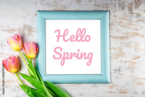  Frame with the inscription Hello Spring and pink tulips on a white wooden background