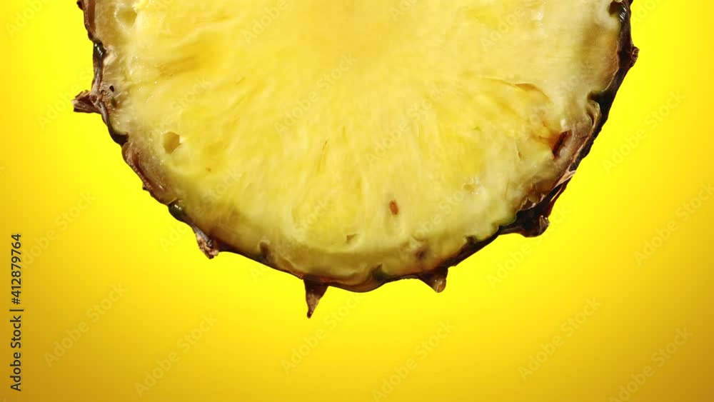 freshly squeezed pineapple juice flows from the ripe fruit slice close - up on a yellow background slow motion freshly squeezed pineapple juice flows from the ripe fruit slice close - up on a yellow background slow motion