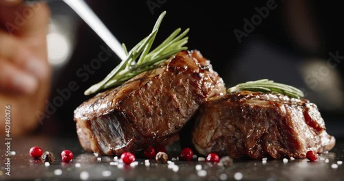 Freshly grilled meat with vegetables. Chef's hand decorates the dish with rosemary