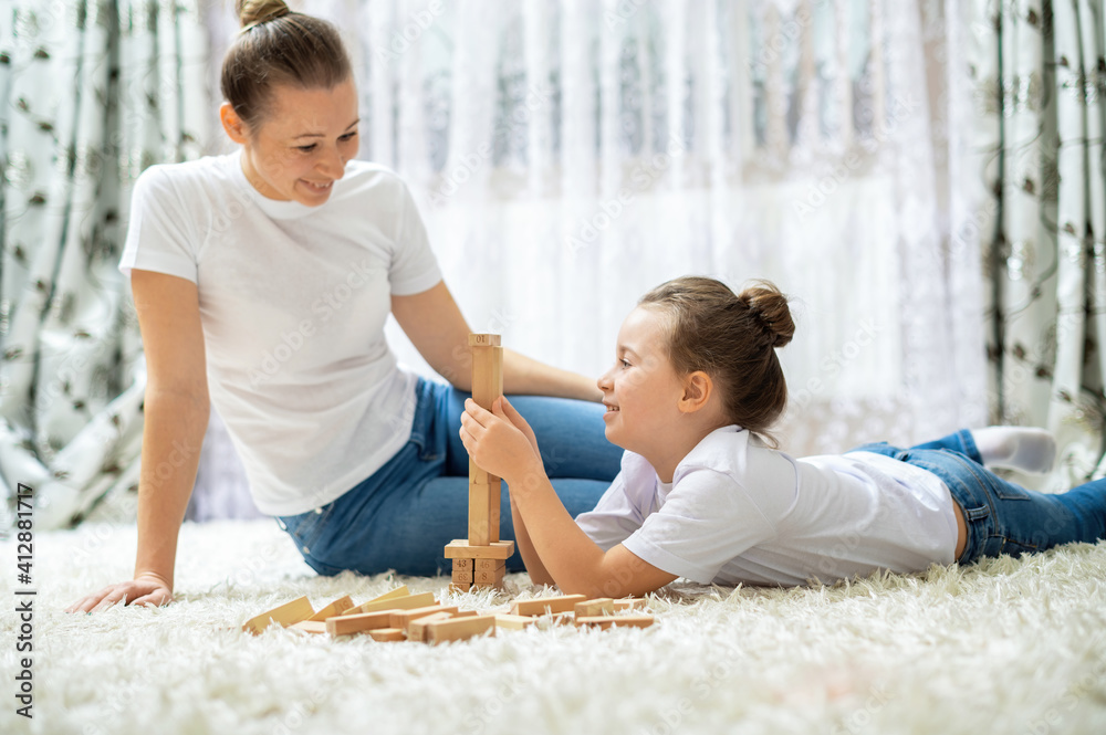 Fototapeta premium Mom and her daughter are playing together at home