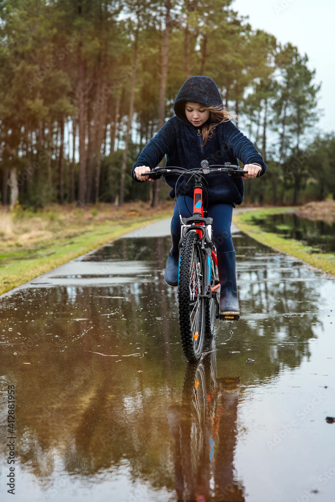 Fototapeta premium beautiful young girl playing while rolling in puddles