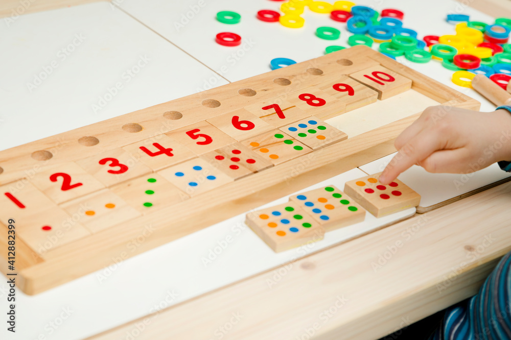 Child playing with different color wooden rings. Sequence, fine motor skills, therapy task for education and brain exercise. Counting math play game. Montessori type implement. Wooden toys. Child playing with different color wooden rings. Sequence, fine motor skills, therapy task for education and brain exercise. Counting math play game. Montessori type implement. Wooden toys.