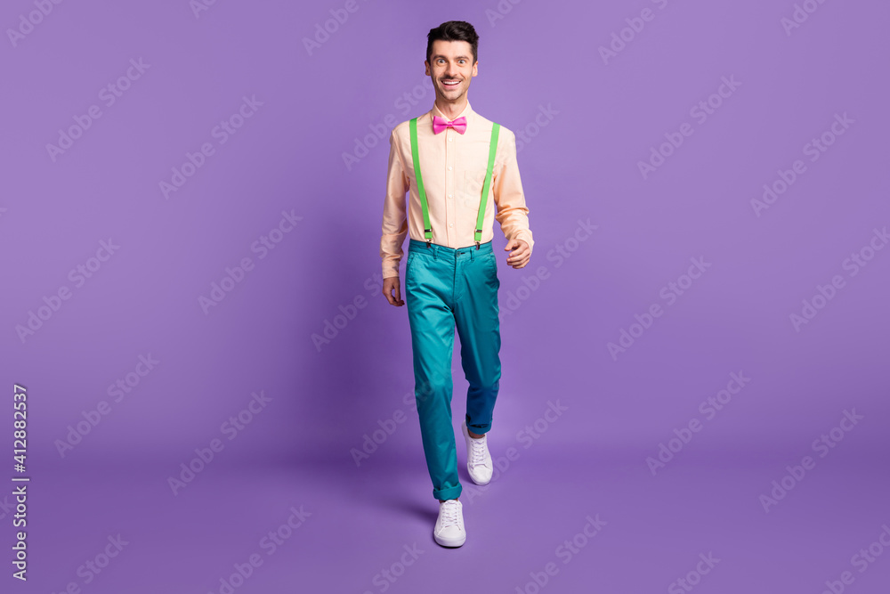 Photo of charming handsome young man dressed yellow shirt walking isolated purple color background Photo of charming handsome young man dressed yellow shirt walking isolated purple color background