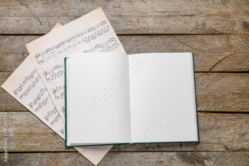 Canvas Print Blank open book and music notes on wooden background