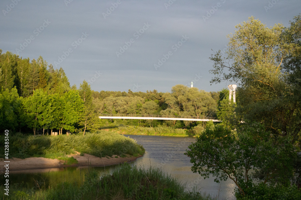 cable-stayed bridge over the river on a sunny summer day with green trees on the river bank.