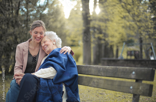 Картината върху платно Granddaughter sitting on a bench in a park with her grandmother and hugging her